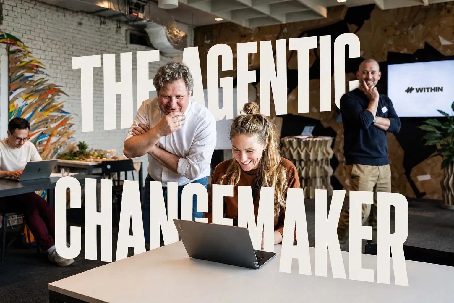 The Agentic Changemaker: participants smile at a laptop during a live day at WITHIN.